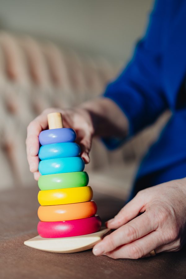 Hands stacking colourful wooden rings
