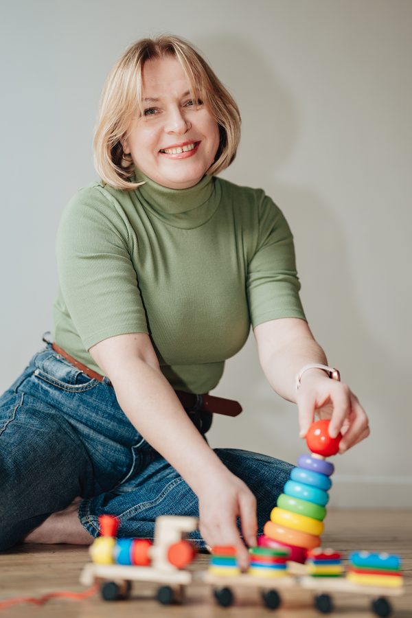 Nadiia smiling while playing with a wooden stacking toy